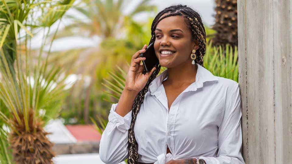 Woman on the phone outdoors, with the surroundings of Apartments di Kurason pa bo on Boneiru in the background